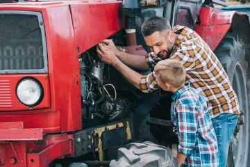 Zelfklevend Fotobehang Tractor happy father and son repairing tractor engine together