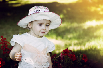 Little girl looks at the flowers of the garden