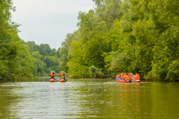 A group of people in life jackets floating on the river on inflatable catamarans. Active rest, healthy lifestyle, hls