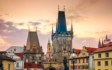Malostranskie bridge towers (Lesser Town Bridge Tower) on the Charles Bridge in Prague, in the Czech Republic at sunset in autumn. Sculptures and lights on the Charles Bridge