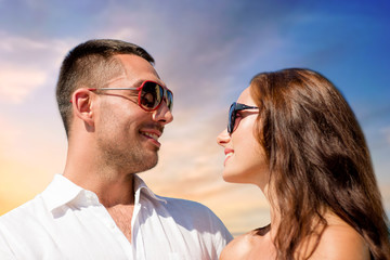 love, summer and relationships concept - happy smiling couple in sunglasses over sky background