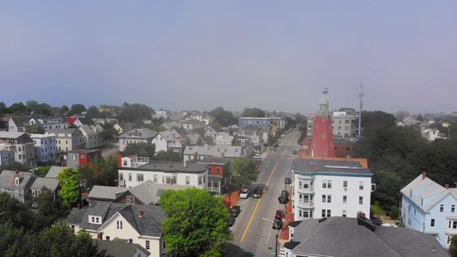 A foggy daytime reverse aerial view of the business district along Congress Street in Portland, Maine. The Portland Observatory is seen in the distance.  	