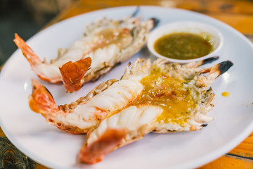 Two grilled giant freshwater river prawns jumbo sized, served with Thai spicy seafood sauce, Thailand famous delicious menu. Asian exotic food, Asia tourism, or Thailand tourist attraction concept
