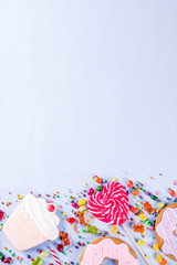 Sweets creative lay out, dessert concept with lollipops, jellies, candy, cookies donuts and cupcakes, light blue background top view copy space