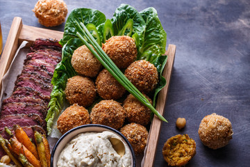 Close view of falafel, babaghanoush and pastrami in the wooden box, copyspace.