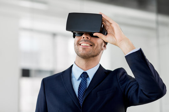 business, technology and augmented reality concept - smiling businessman with vr headset at office