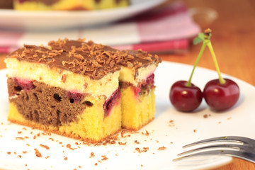 Cocoa cherry cake, called 'Danube Wave'. Top with vanilla cream and chocolate. Plate with two slices of cake on the wooden table.