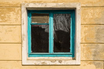 Old window in an abandoned house with blue wooden frame