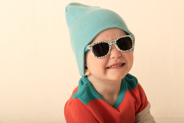 Happy charming Caucasian blond kid in colored clothes playing with plastic letters. Learning the...