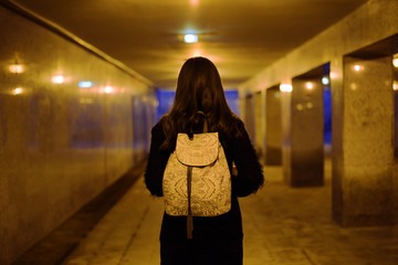 Portrait of a brunette in the underpass from the back with a white backpack