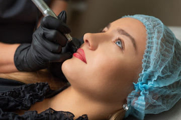 A young girl having lips permanent makeup, micropigmentation. - obrazy, fototapety, plakaty