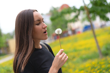 Portrait of a girl blowing on a dandelion in her hand