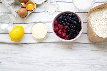 Raw ingredients: berries, lemon, eggs, flour, sugar, salt, water for cooking berry pie, view from above.  Overhead, flat lay. Copy space.