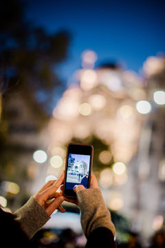 Woman taking with her smartphone photo at dusk of the Casa Batllo by Antoni Gaudi, Barcelona, Catalonia, Spain