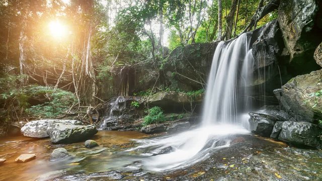 Beautiful mountain waterfall in the jungle forest of Thailand. Water flow and fall down from high mossy rock. Green tree tropical foliage in sunset soft light. 4K Slow Motion Photo Time Lapse Parallax