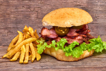 Barbeque Pulled beff Sandwich with green salad,crisp bacon,hot pepper jalapeno,BBQ Sauce and Fries on wooden background,Fast food