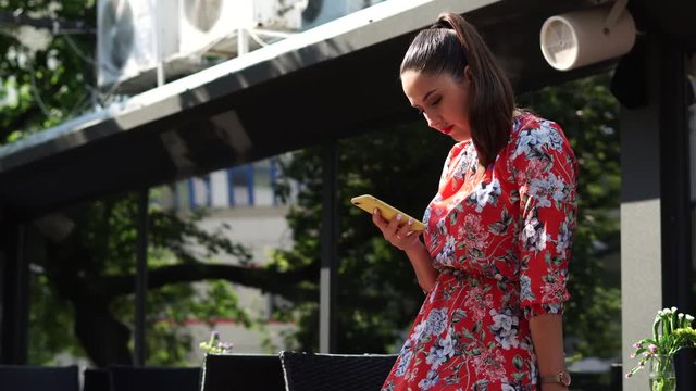 Beautiful girl in red dress, with flower pattern on the terace, outdoor in business centr.