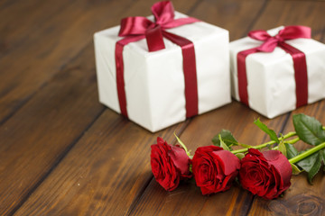 Red roses and gift box on brown wooden table
