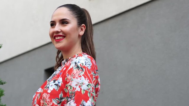 Beautiful girl in red dress, with flower pattern on the terace, outdoor in business centr.
