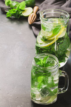 Mojito cocktail in mason jar with mint and lime on black stone table. Copy space for text.