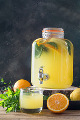 Summer healthy detox drink. Lemonade with orange, lemon and mint in mason jar on wooden board.