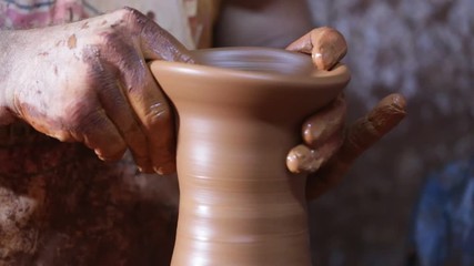 Giving shape to the pottery with hand on pottery wheel camera tilt
