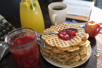 breakfast waffles with homemade jam, coffee, lemonade, apple and a book on a table