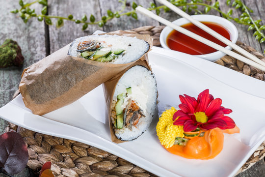 Sushi burrito rolls with salmon, cream cheese, avocado and cucumber on plate. Japanese Cuisine - healthy sea food.