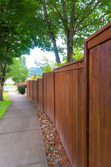 Wooden stained Fence along suburban Neighborhood Sidewalk
