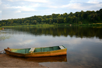 old wooden boat on the river bank. picturesque water landscape.calm and relaxing summer evening