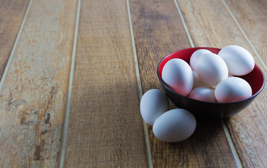 Close up white chicken eggs, inside a bowl, on a wooden table.