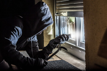 ein maskierter Einbrecher beabsichtigt in ein Haus einzubrechen - obrazy, fototapety, plakaty