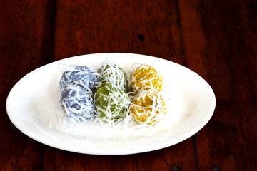 Thai coconut muchkins on white ceramic plate on wood table,  Thai tradition sweet