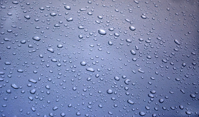 large and small drops of water on a blue bright background