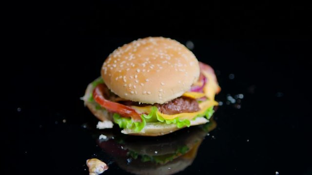 The fist smashes burger into pieces. Black mirror surface