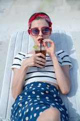 Girl in a chaise longue with a cool drink in her hand