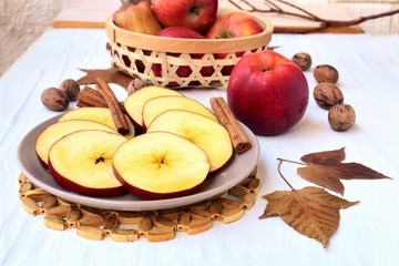 Naklejka na ściany i meble Round sliced apple with honey, fall leaves and nuts, on a veranda table, autumn still life. 