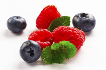 Close-up arrangement mixed, assorted berries including blackberries, strawberry, blueberry, raspberries and fresh leaf on white