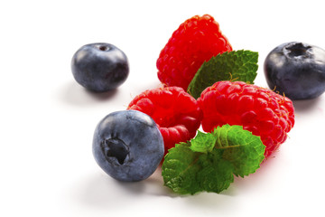 Close-up arrangement mixed, assorted berries including blackberries, strawberry, blueberry, raspberries and fresh leaf on white