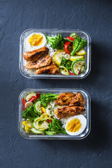 Rice, stewed vegetables, egg, teriyaki chicken - healthy balanced lunch box on a dark background, top view. Home food for office concept
