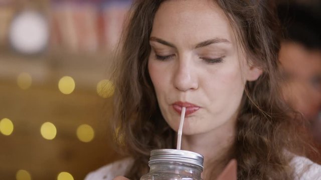 Attractive young female drinking in a coffee shop as she checks her phone