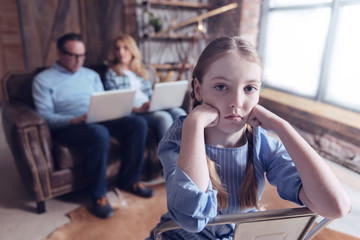 Neglected child. Unhappy depressed nice girl holding her cheeks and feeling upset while sitting on...