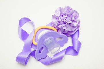 Pacifier with a lilac ribbon and bow.