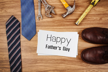 Happy Father's Day card with old rusty tools and tie on wooden background