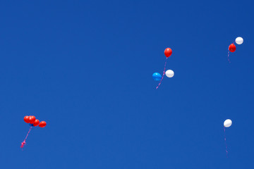 Group of multicolored helium filled balloons in the sky .