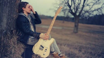 young man playing guitar at sunset