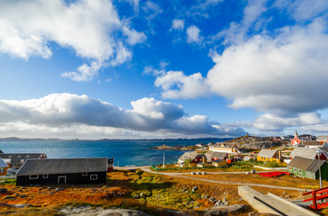 Fototapeta na wymiar Nuuk city old harbor fjord panorama with clouds over the blue sky in the background, Greenland
