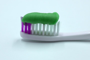 Blue toothbrush with green toothpaste isolated on a white background .
