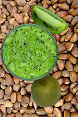 Healthy fresh kiwi smoothie in glass on a wooden background .