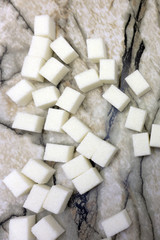 Refined sugar in a glass saucer. On a stone background.